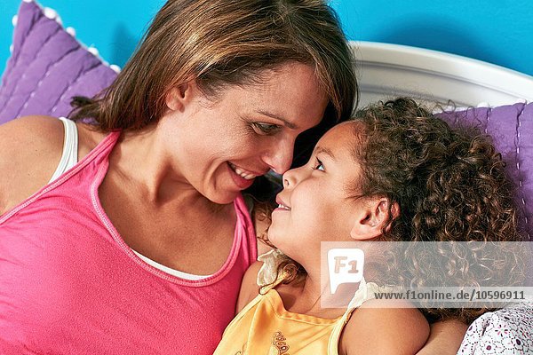 Mutter und Tochter im Bett Nase an Nase lächelnd