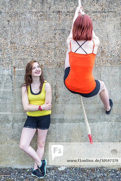 Junge Frauen klettern mit Seil über die Wand