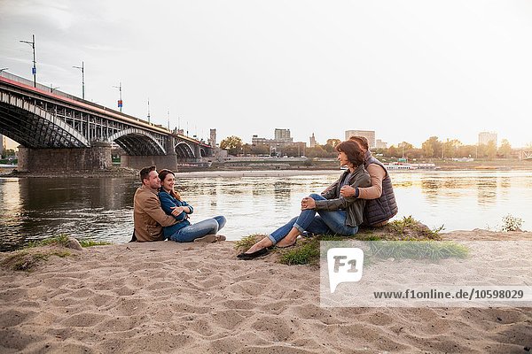 Four friends sitting on riverbank  Warsaw  Poland