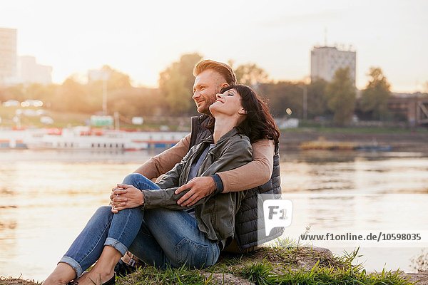 Mid adult couple sitting by river relaxing