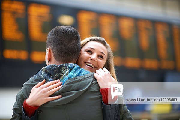 Heterosexual couple hugging at railway station  rear view
