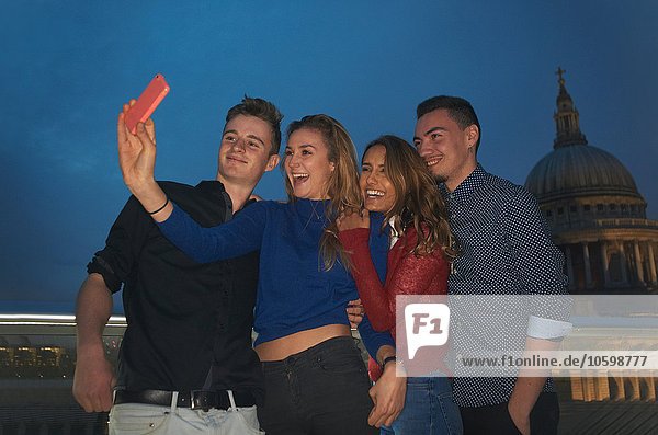 Zwei junge Paare mit Smartphone-Selfie vor St. Pauls bei Nacht  London  UK