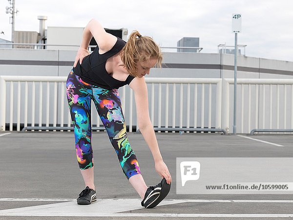 Young woman doing stretch training in parking lot