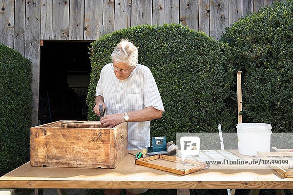 Senior Mann macht Holzkiste im Garten