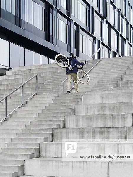 Stadtradfahrer mit Fahrrad aufsteigender Treppe