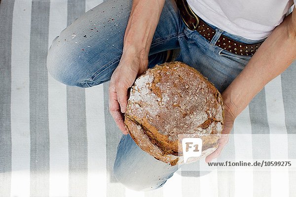Overhead-Ansicht einer reifen Frau auf gestreiftem Teppich mit frisch gebackenem Brot