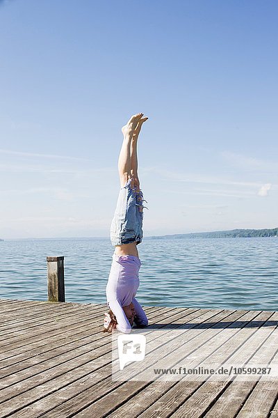 Reife Frau am Pier am Meer balanciert auf dem Kopf