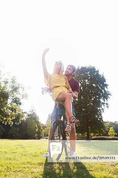 Junges Paar auf dem Fahrrad mit Smartphone Selfie im sonnigen Park