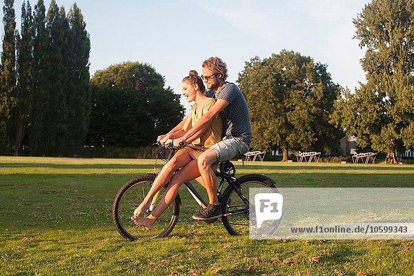 Romantic young couple on bicycle together in park