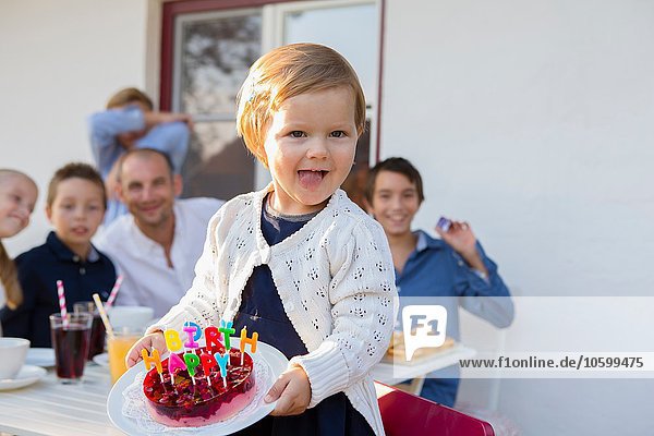 Kleinkind mit Geburtstagskuchen auf der Terrasse