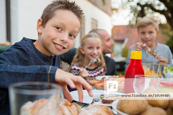 Portrait of boy and family at garden barbecue table