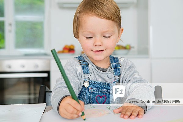 Female toddler drawing at kitchen table