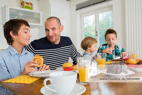 Mid adult man and family having tea at kitchen table