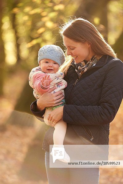 Portrait of mid adult woman and baby daughter in autumn park