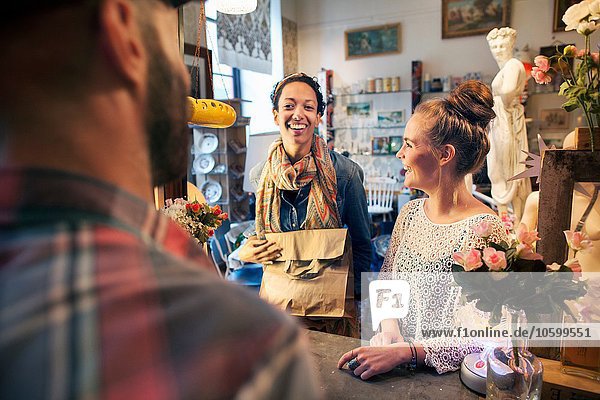 Zwei glückliche junge weibliche Kunden  die im Vintage-Shop einkaufen.