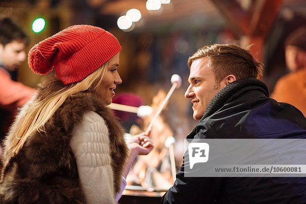 Young couple toasting marshmallows at xmas festival in Hyde Park  London  UK