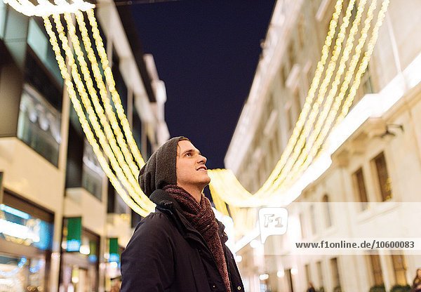 Junger Mann schaut auf Weihnachtsbeleuchtung  London  UK