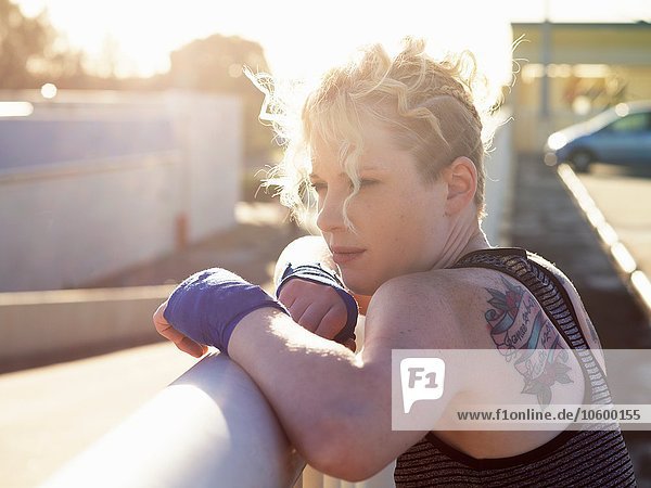 Porträt einer jungen Boxerin  die sich an ein städtisches Geländer lehnt.