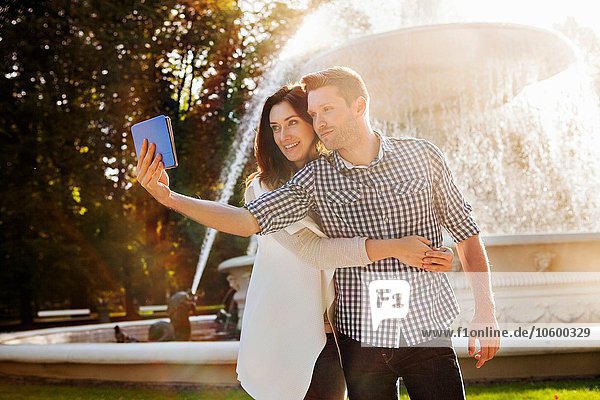 Paar nimmt Selfie auf digitalem Tablett im Park auf