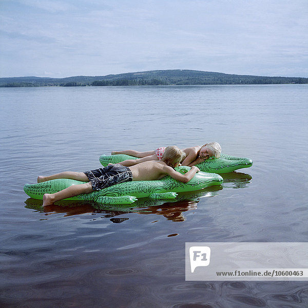 Boy and girl lying on inflatable in lake