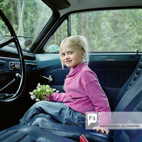 Mädchen mit Blumen im Auto sitzend  lächelnd