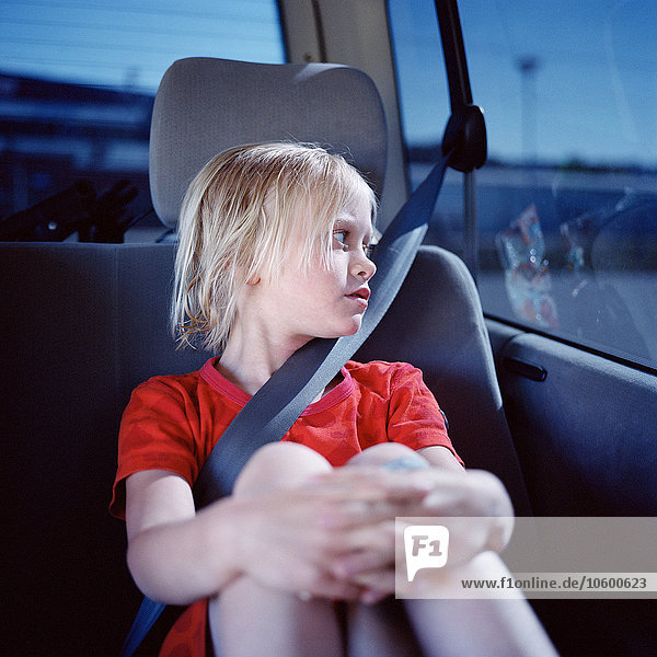 Mädchen sitzt im Auto und schaut durch das Fenster