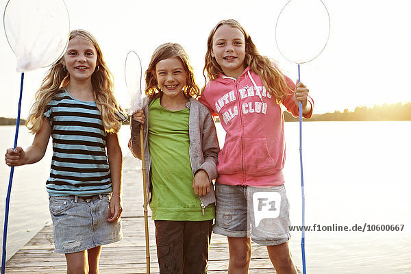 Drei Mädchen stehen mit Fischernetzen