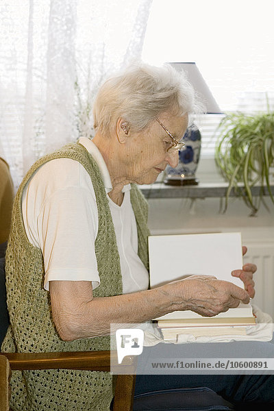 Ältere Frau liest ein Buch in einem Haus