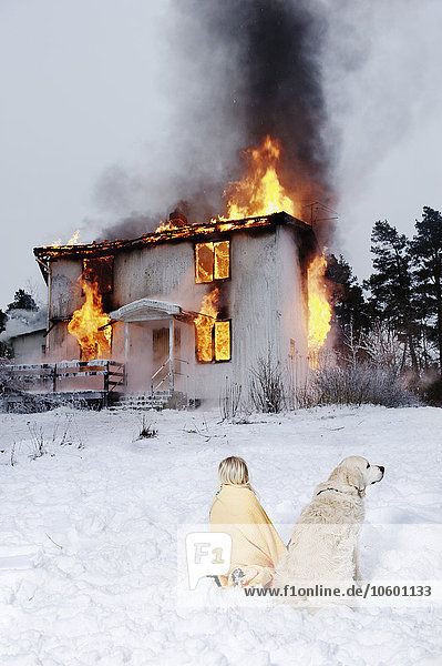 Gerettetes Mädchen mit Hund vor brennendem Haus