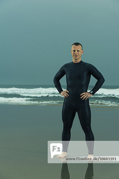 Man wearing wetsuit and standing on beach