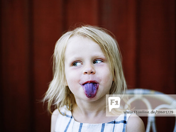 Mädchen streckt blaue Zunge heraus