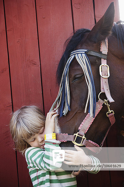 Junge  der ein Pferd umarmt