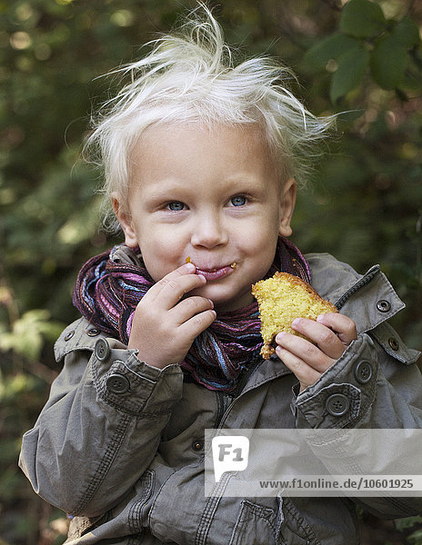 Lächelnder Junge isst Biskuitkuchen