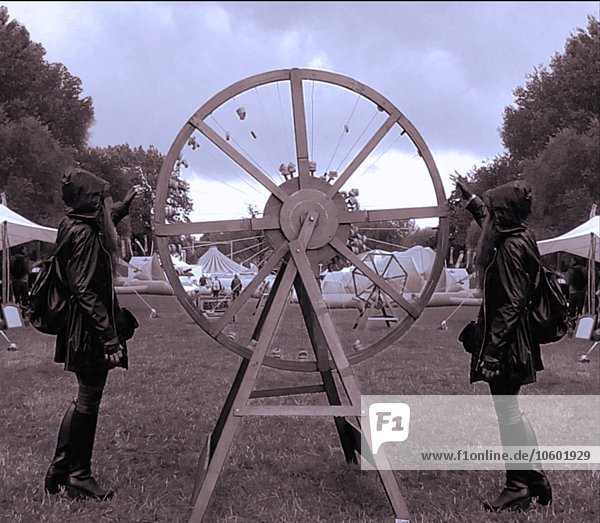 Illusion von zwei jungen Frauen  die beim Karneval ein großes Rad drehen