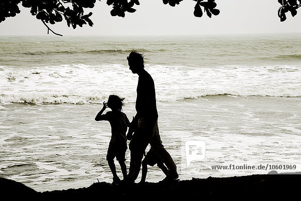 Silhouette of father and son walking on beach