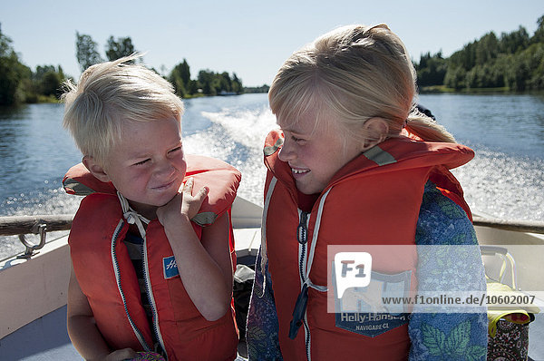 Boy and girl wearing life vests on boat