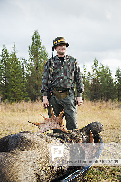 Smiling man with dead elk at hunting