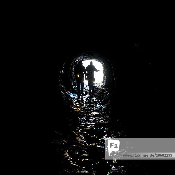 Menschen mit Taschenlampe betreten Höhle