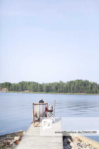 Man sitting on jetty with Dalmatian  Finland