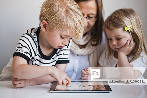 Großmutter mit Enkelkindern  die ein digitales Tablet benutzen
