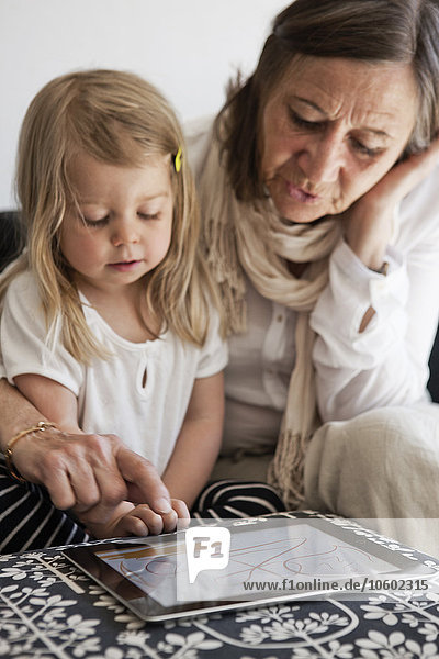 Grandmother with granddaughter using laptop