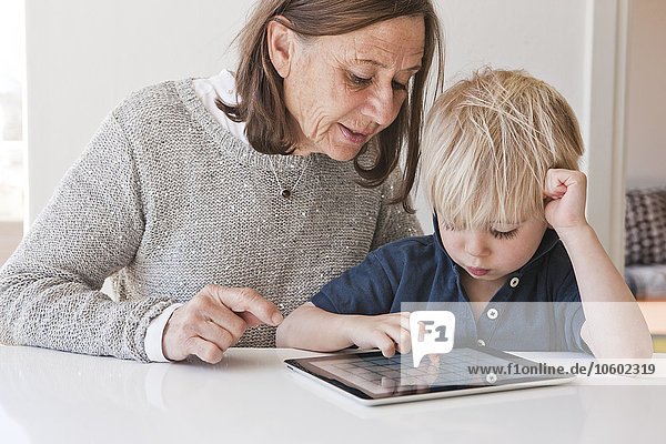 Großmutter mit Enkel  der ein digitales Tablet benutzt