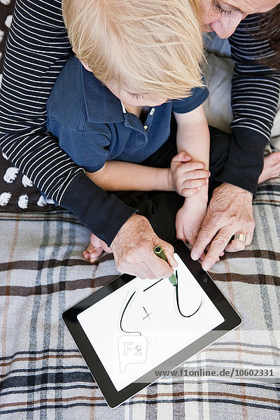 Großmutter und Enkel benutzen ein digitales Tablet