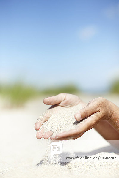 Nahaufnahme der Hände einer Person  die Sand verschüttet
