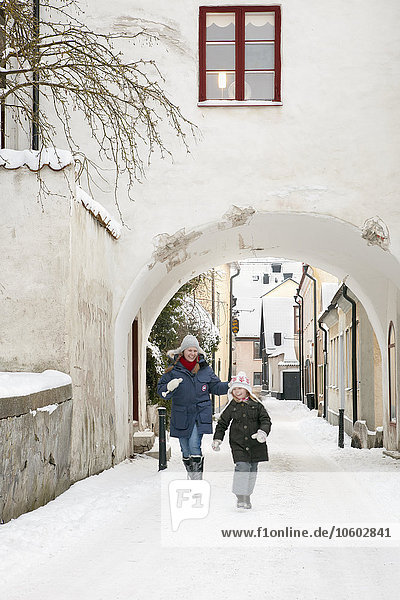 Mutter mit Tochter läuft auf verschneiter Straße