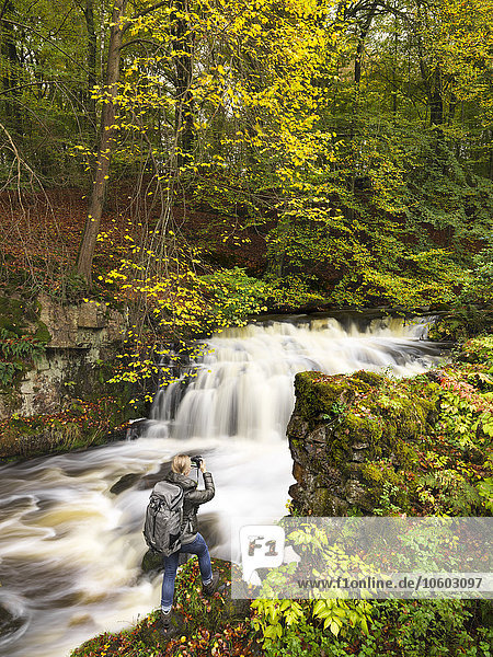 Woman taking photo of waterfall