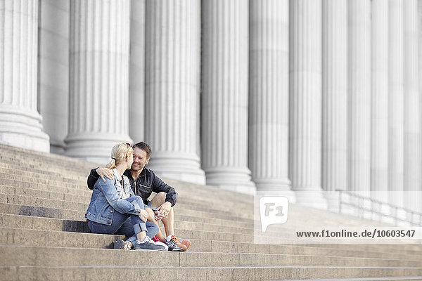 Couple sitting on steps  columns on background