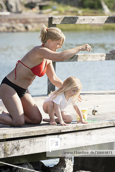 Mother with daughter fishing on jetty