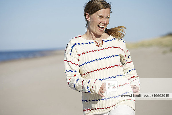 Glückliche Frau joggt am Strand