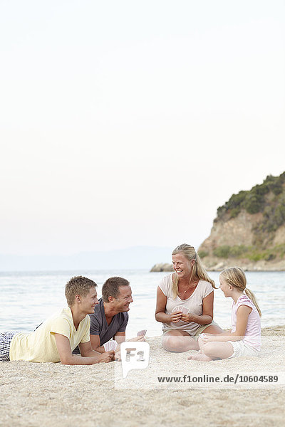Familie spielt Karten am Strand
